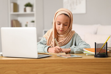 Sticker - Little Muslim girl in hijab doing homework at home