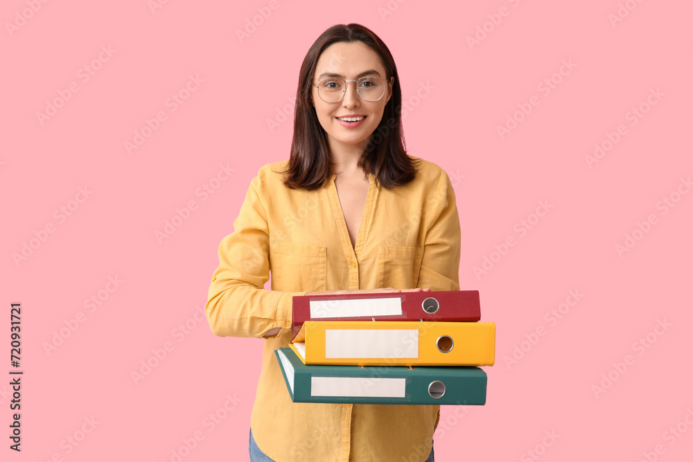 Young businesswoman with document folders on pink background