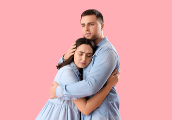 Poster - Sad young woman hugging her husband on pink background