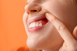 © Pixel-Shot - Teenage girl showing her teeth on orange background, closeup