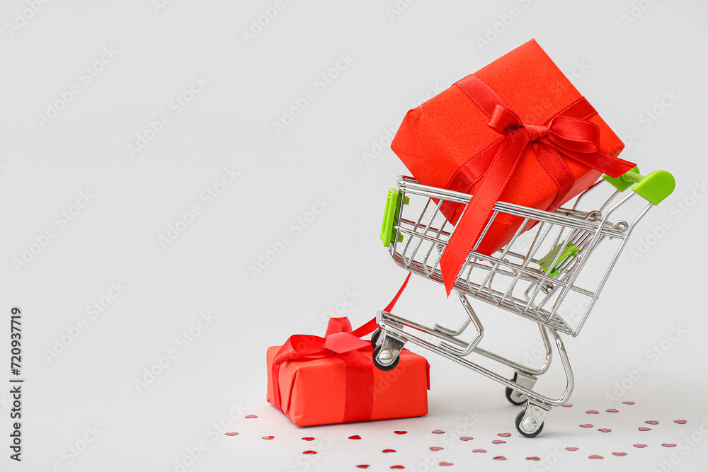 Small shopping cart with gift boxes on white background. Valentine's Day celebration