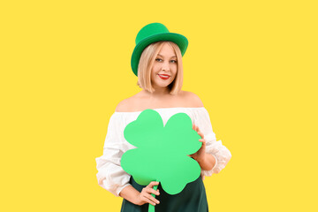 Poster - Happy woman with paper clover on yellow background. St. Patrick's Day