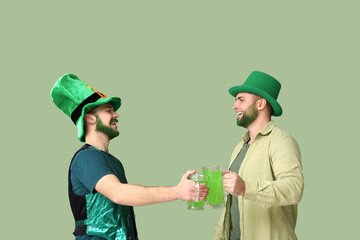 Wall Mural - Young men in leprechaun hats with green beards holding glasses of beer on green background. St. Patrick's Day celebration