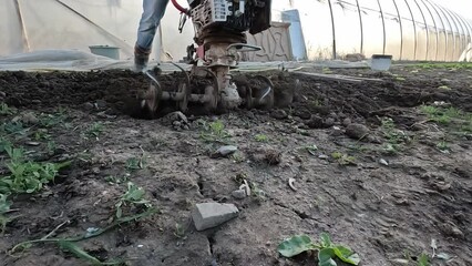 Wall Mural - Farmer working in cultivating soil with manual motor plow, work on plowing land