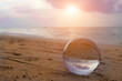Beautiful scenic view through lens of crystal ball on water horizon at summer sunset. Clouds reflection in sphere.