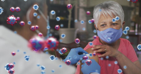 Poster - Covid-19 cells floating against male doctor giving covid 19 vaccine to senior woman