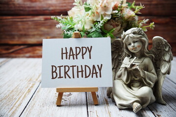 Canvas Print - Happy Birthday text message written on paper card with wooden easel and angel statue with flower in metal vase decoration