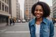 Young hipster black woman in a stylish denim jacket walking in the street, smiling and looking at the camera.