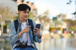 © saltdium - A Handsome backpacked male tourist using his mobile phone at Chiang Mai moat on the background with copy space, Solo travel concept