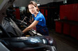 © Svitlana - Young woman works under the open hood of a car
