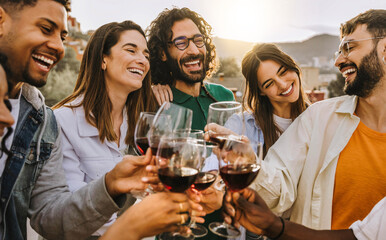 Wall Mural - Happy friends toasting red wine glasses outside - Group of young people having bbq dinner party in backyard house - Winery and bbq dining concept with guys and girls cheering alcohol together