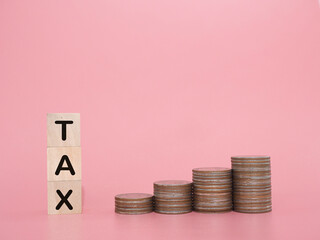 Wooden blocks with the word TAX and stack of coins. The concept about saving money and manage time to paying tax