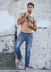 Poster - Fashion, city and portrait of man by wall in trendy, casual and stylish outfit in nature. Serious, confidence and full length of attractive young male model undress with cool style by in town.