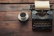 Vintage typewriter with a sheet of paper and a cup of coffee on a wooden desk