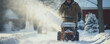 a man clears snow from the sidewalk with a snow blower
