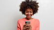 © BeautyStock - happy smiling pretty black woman holding mobile phone looking at smartphone, typing, doing ecommerce online shopping on cell isolated on studio white background, communication technology concept