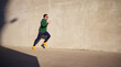 © baranq - Adult athletic man running fast along concrete wall in the city