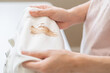 Close up hand of housewife, maid woman holding white t-shirt, showing making cloth stain, spot dirty or smudge on clothes, dirt stains for cleaning before washing, making household working at home.