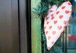 Dekoration mit weißem Herz aus Stoff mit rotem Herzmuster an Hauswand an Valentin