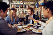 © Davor - Group of friends enjoying a meal together at a cozy restaurant