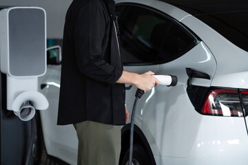 Young man travel with EV electric car to shopping center parking lot charging in downtown city showing urban sustainability lifestyle by green clean rechargeable energy of electric vehicle innards