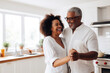 © aamulya - African multiracial married middle aged mature couple dancing in kitchen