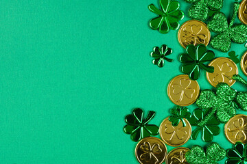 Poster - St Patricks Day side border of  shiny shamrocks and gold coins. Top view over a green background with copy space.