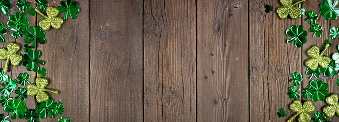 Wall Mural - St Patricks Day double border of  shiny shamrocks. Top view over a rustic dark wood banner background with copy space.