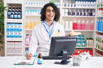 Poster - Hispanic man with curly hair working at pharmacy drugstore pointing aside with hands open palms showing copy space, presenting advertisement smiling excited happy