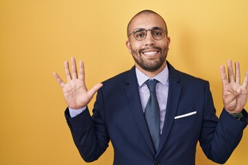 Sticker - Hispanic man with beard wearing suit and tie showing and pointing up with fingers number nine while smiling confident and happy.