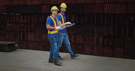 Workers partners in uniform walk and Talking on a Meeting in Metal Construction Manufacture industry factory, Engineers man colleagues industrial discussing project work in warehouse. Team work