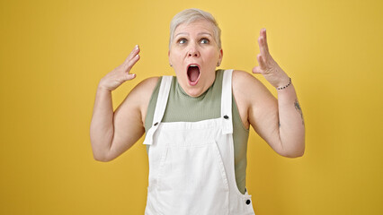 Sticker - Middle age grey-haired woman standing with surprise expression over isolated yellow background