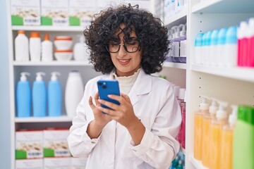 Poster - Young middle eastern woman pharmacist using smartphone working at pharmacy