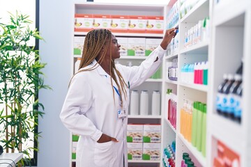 Poster - African american woman pharmacist smiling confident holding deodorant of shelving at pharmacy