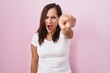 Middle age brunette woman standing over pink background pointing displeased and frustrated to the camera, angry and furious with you
