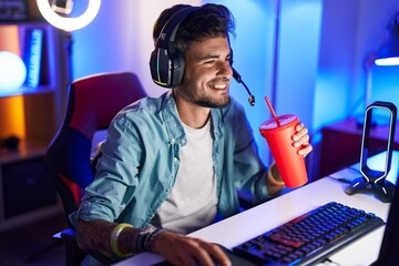 Sticker - Young hispanic man streamer playing video game drinking beverage at gaming room