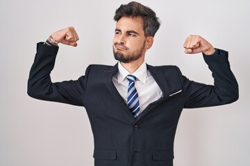 Poster - Young hispanic man with tattoos wearing business suit and tie showing arms muscles smiling proud. fitness concept.