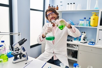 Sticker - Middle age man scientist pouring liquid on test tube at laboratory