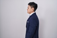 Young Asian Man Wearing Business Suit And Tie Looking To Side, Relax Profile Pose With Natural Face And Confident Smile.