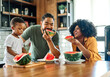 © Lumos sp - child family kitchen food boy son father mother watermelon fruit slice summer organic meal fun preparing healthy diet eating home black