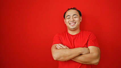 Sticker - Laughing handsome young asian man exudes confidence, standing with arms crossed over red background, embodying joy and positivity