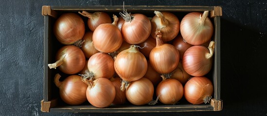 Wall Mural - Box of Brown Onions over Black Background: The Perfect Box of Brown Onions for a Savory Delight on an Alluring Black Background