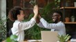 Two happy friendly diverse professionals, teacher and student giving high five standing in office celebrating success