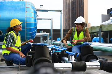 Wall Mural - Diversity engineers wearing reflect green  safety vests and helmet  working to checking Industry cooling systems, and HVAC of large industrial building 