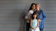 © fizkes - Photo portrait of three beautiful females of diverse generations one hispanic family. Preteen kid girl sit on chair while adult mum and older grandma stand behind embrace her look at camera. Copyspace