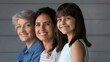 © fizkes - Childhood youth and retirement. Portrait of smiling junior school age latin girl looking at camera together with young mother and aged grandma. 3 different women members of latina family posing in row