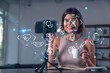 © VideoFlow - Happy woman is making video blog using smartphone on a tripod explaining with hands at office workplace. Concept of online stream, business education, conference call. Medical health care hologram