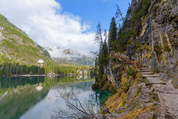 Wall Mural - beautiful landscape of mountain lake Braies in the Dolomites, Italy. Hiking trail along the lake and low clouds over the mountain