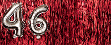 Silver Foil Balloon Number 46 On A Background Of Red Tinsel Decoration. Birthday Greeting Card, Inscription Forty-six. Anniversary Event. Banner.