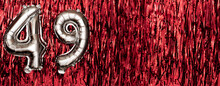 Silver Foil Balloon Number 49 On A Background Of Red Tinsel Decoration. Birthday Greeting Card, Inscription Forty-nine. Anniversary Event. Banner.